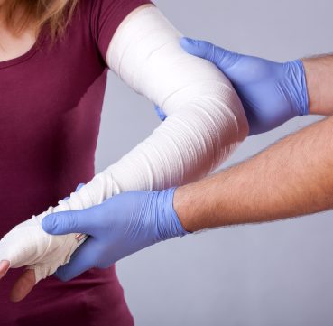 A doctor checking up a bandages arm of a patient